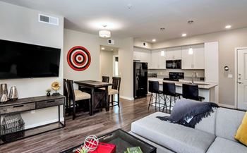 A modern living room with a grey couch and a television on the wall.